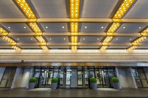 Une entrée d’hôtel moderne, avec un plafond au design géométrique et un éclairage encastré.
