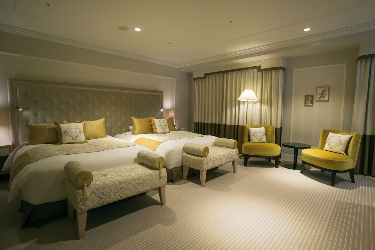 A hotel room with a large bed, two armchairs, a small table, and a lamp.