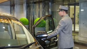Un empleado de hotel abriendo la puerta de un automóvil.