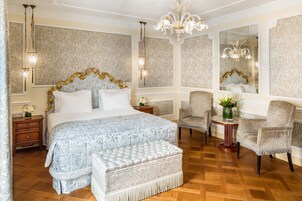Camera da letto con un letto grande, un lampadario, carta da parati decorata e uno specchio.