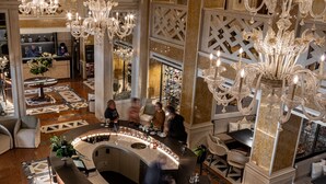 A luxurious lobby with a central bar, ornate chandeliers, and a patterned floor.