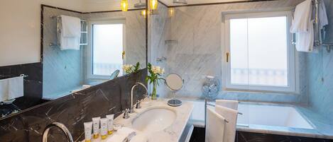 A modern bathroom with two sinks, a large mirror, and a bathtub.