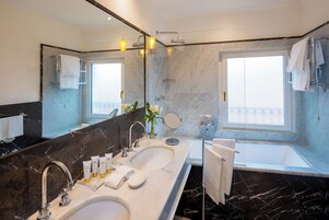 A modern bathroom with two sinks, a large mirror, and a bathtub.