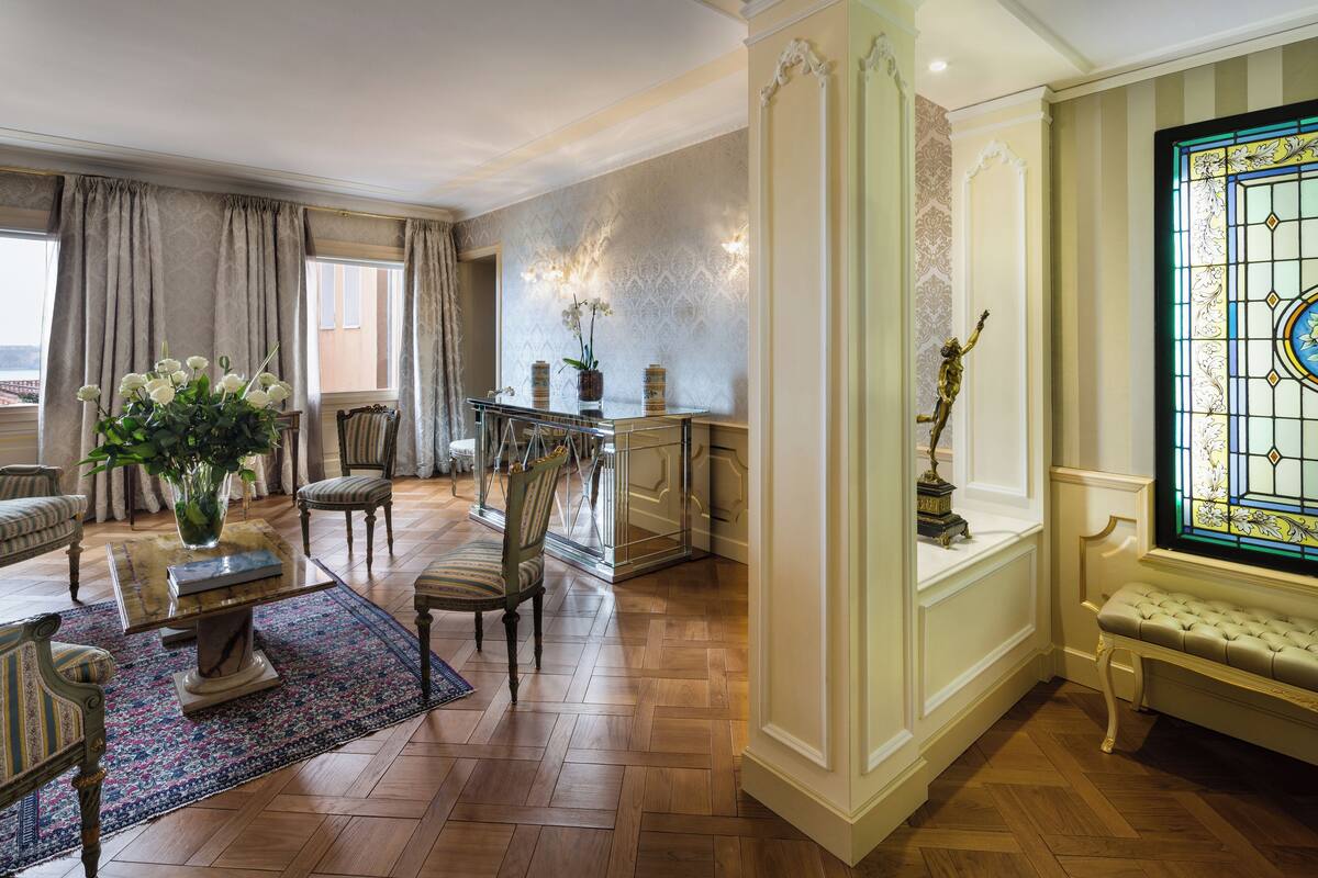 Un vaste salon doté d’un plancher en bois, d’une table basse, d’un canapé et d’un coin repas avec des chaises et un lustre.