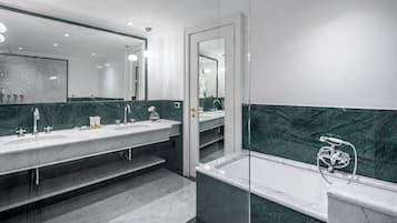 A modern bathroom with two sinks, a bathtub, and a large mirror.