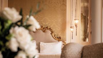 A luxurious bedroom with a large bed, a chandelier, and a mirror.
