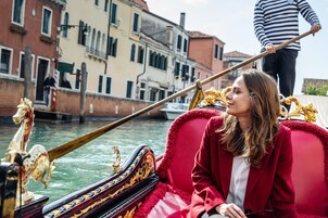 A gondola with ornate decorations and a person in a red coat.