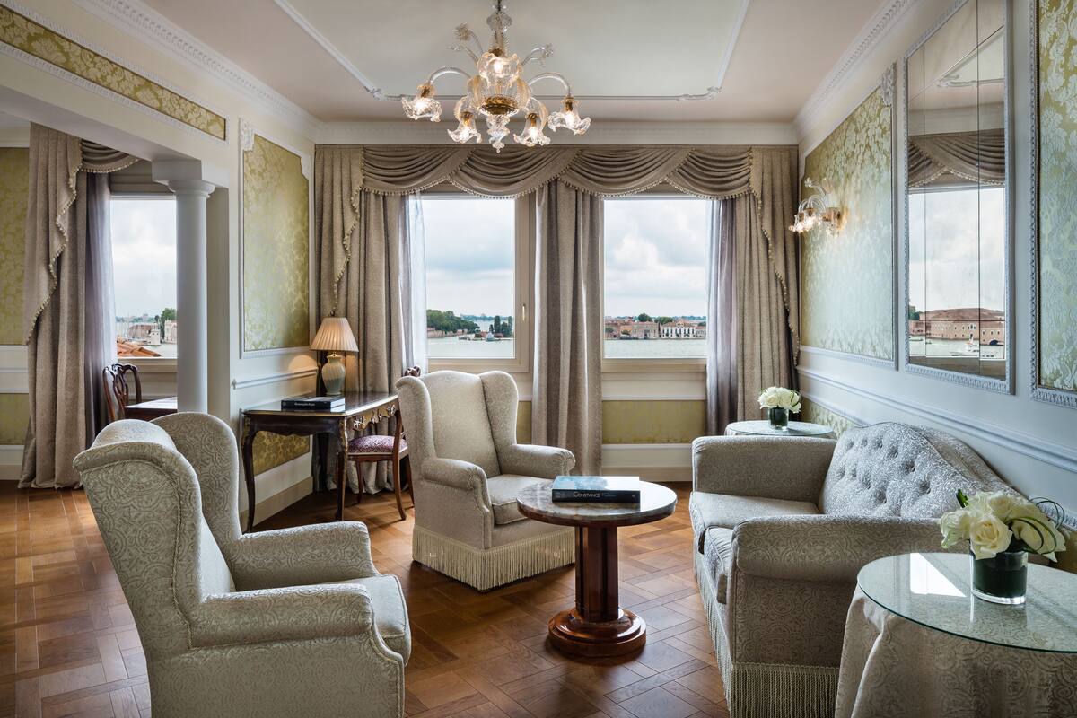 Une chambre luxueuse dotée d’une grande fenêtre, d’un mobilier élégant et d’un lustre.