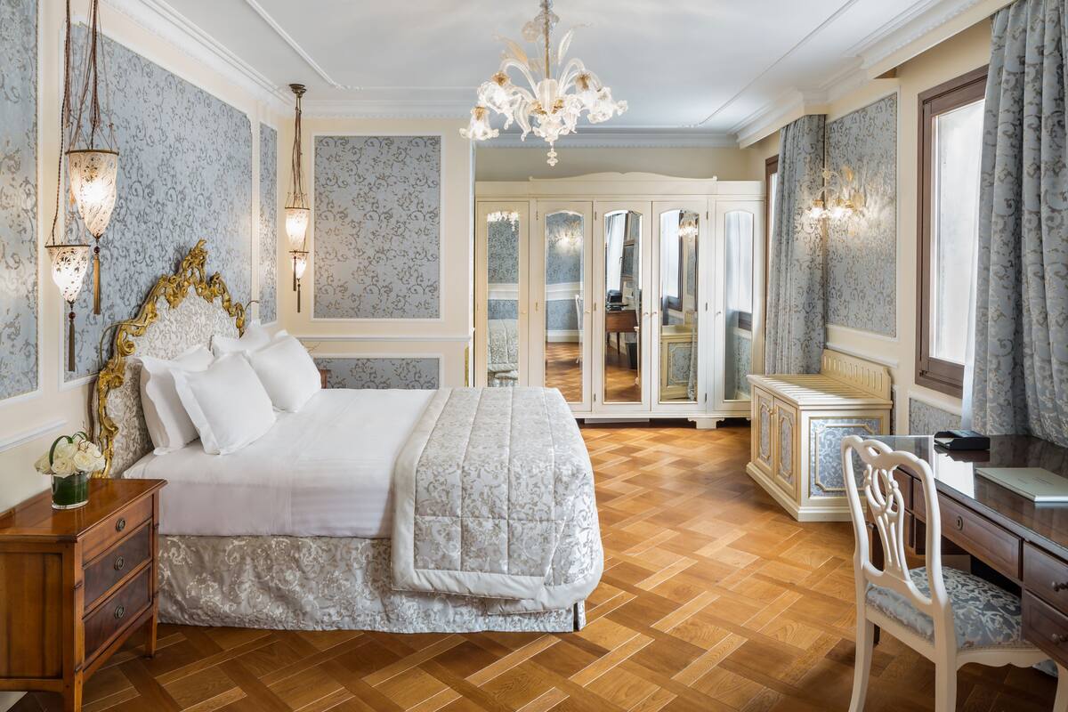 Une chambre à coucher avec un grand lit, une table de chevet en bois, une chaise, une commode et un miroir.
