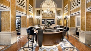 A luxurious bar area with marble flooring, a central bar counter, and multiple seating options.