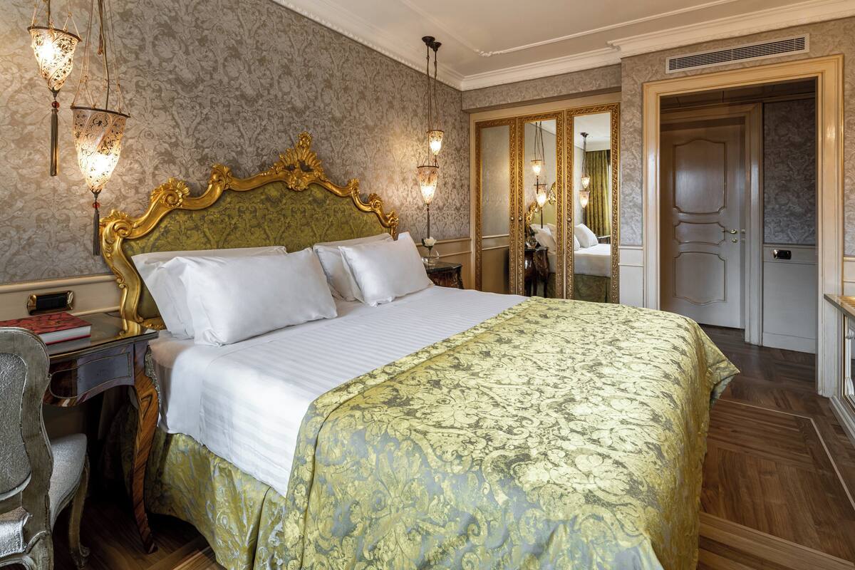 Une chambre à coucher luxueuse, dotée d’un grand lit, d’une tête de lit décorée et d’un miroir.