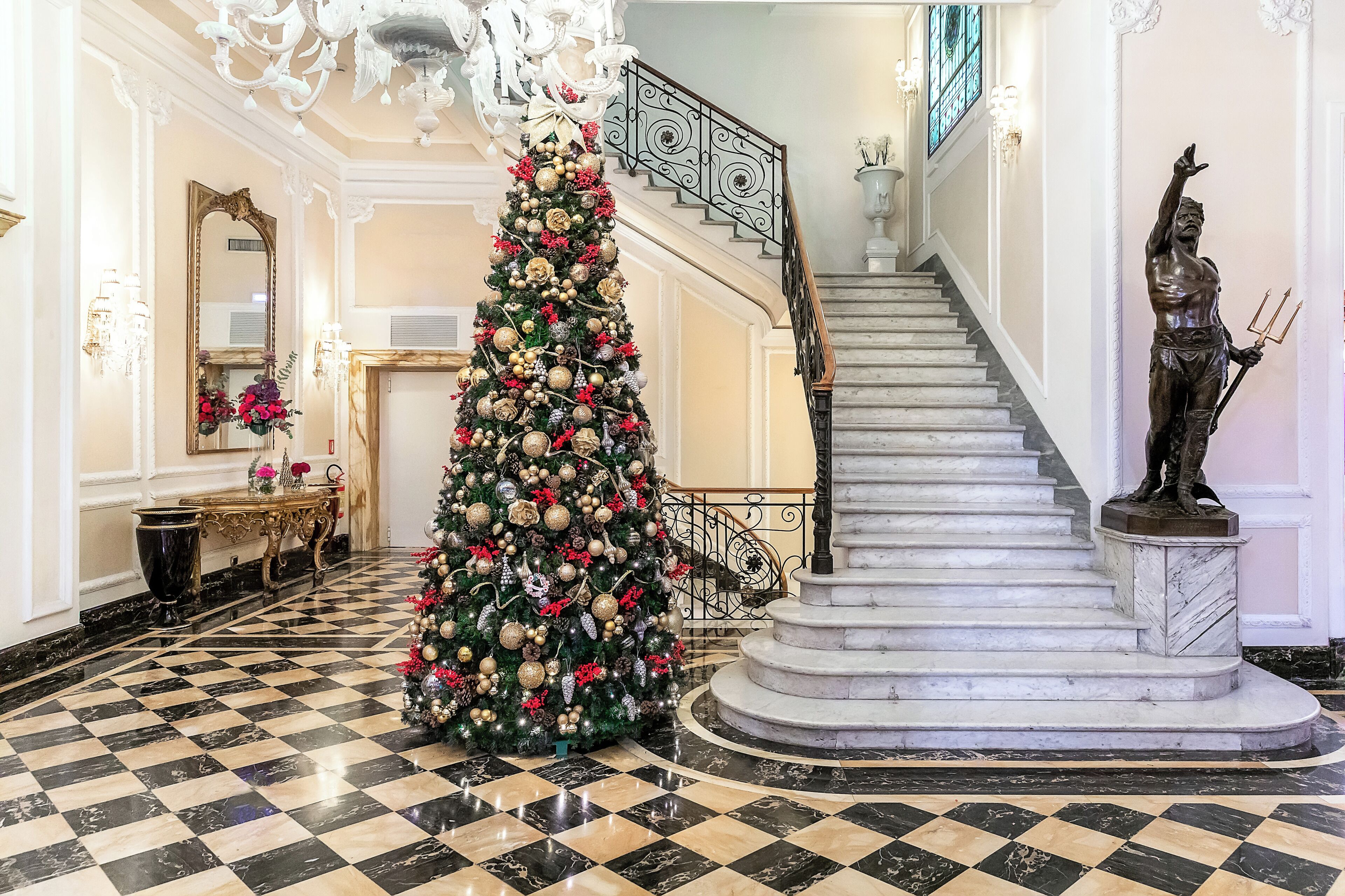 Ein prachtvoller Eingangsbereich mit einem großen Weihnachtsbaum, einer Marmortreppe und einer Statue.