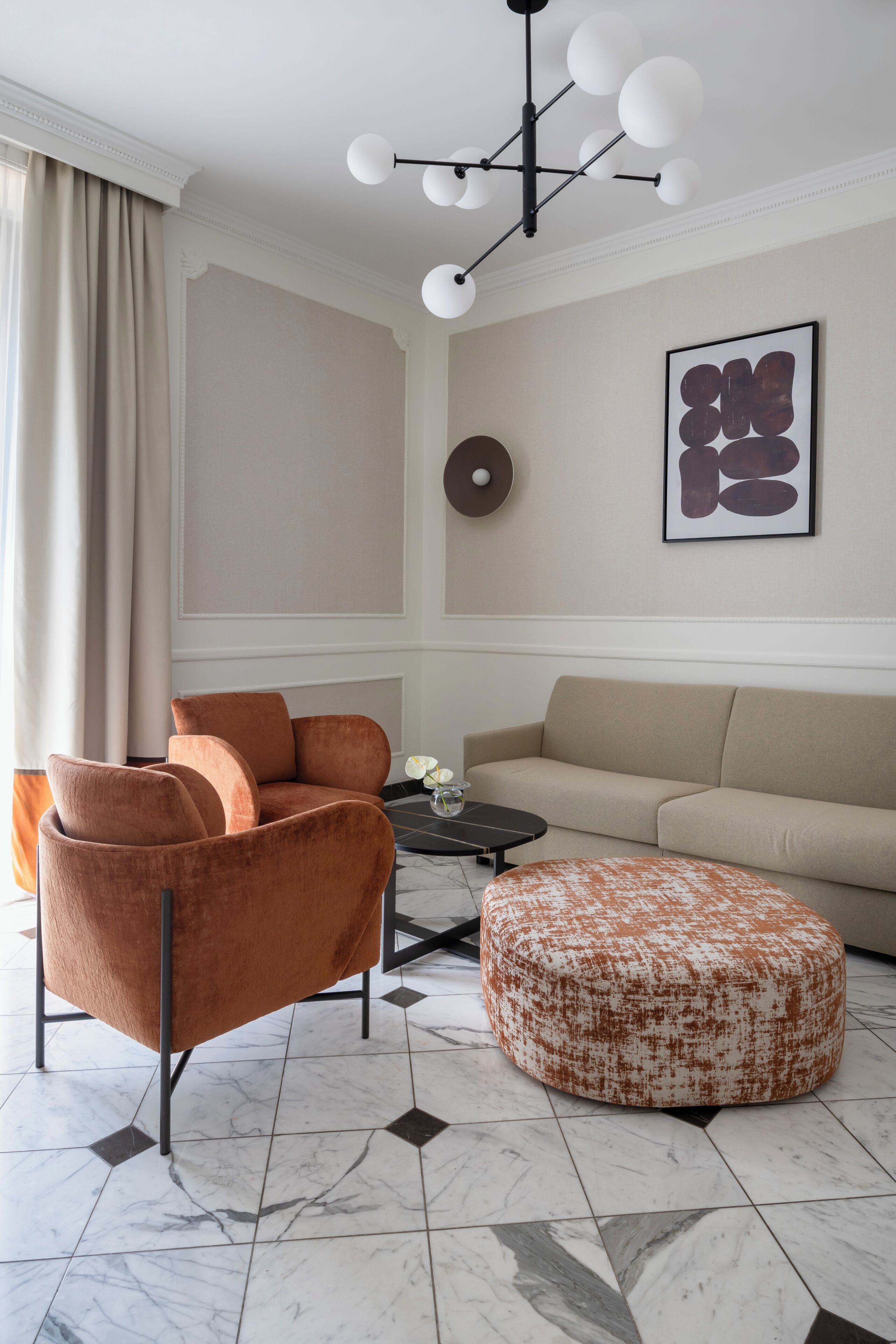 A modern living room with a sofa, armchair, ottoman, and a coffee table.