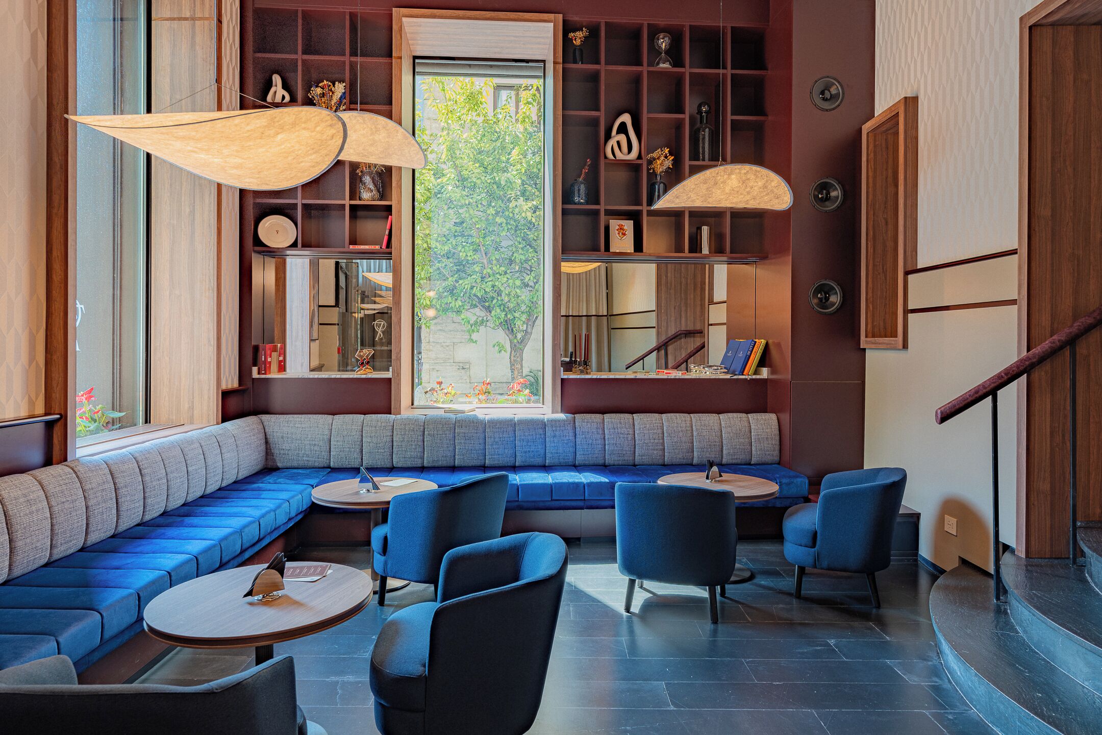 Ein modernes Interieur mit integriertem Sitzbereich, runden Tischen und einer Treppe.