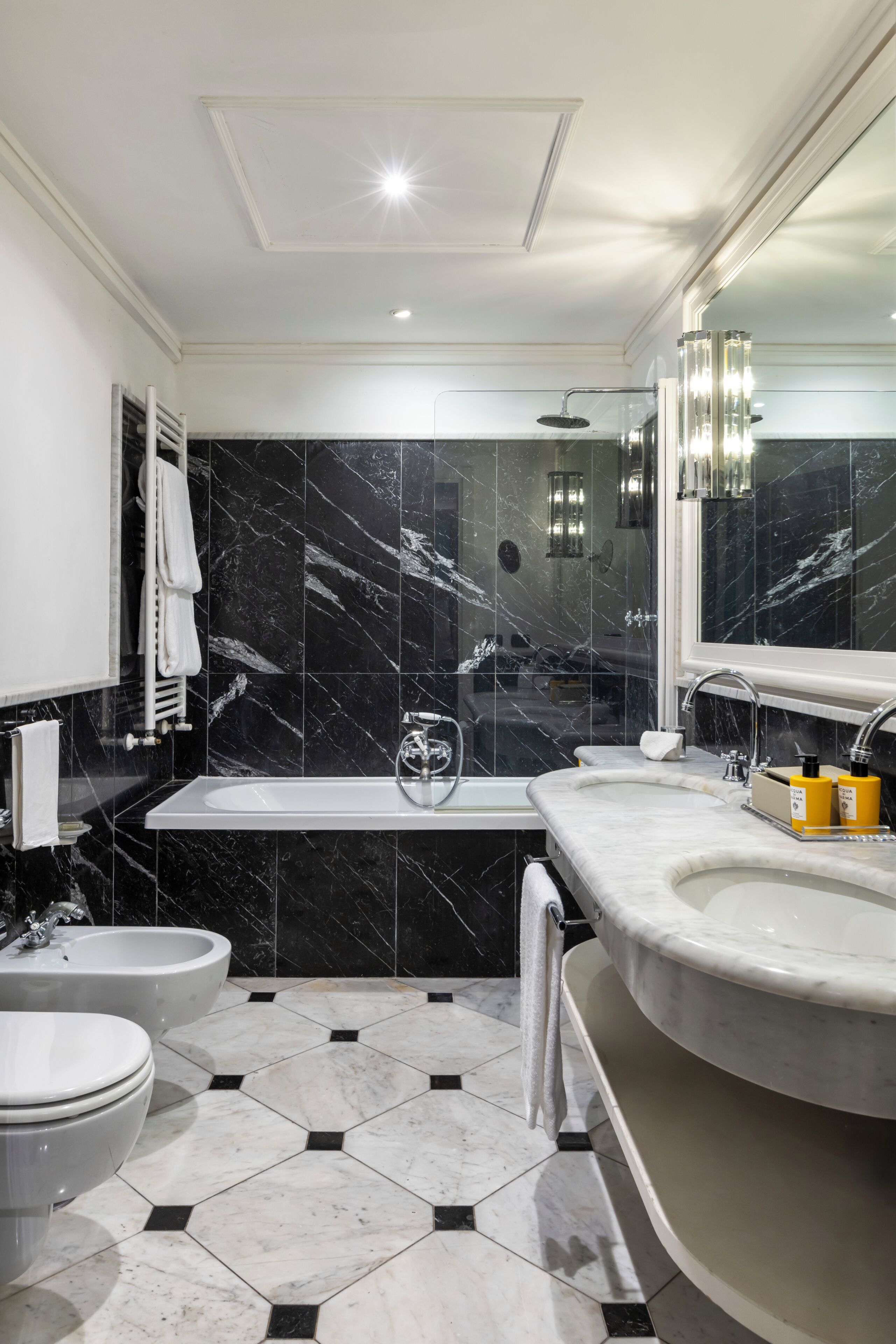 A modern bathroom with a bathtub, two sinks, a toilet, and a shower.