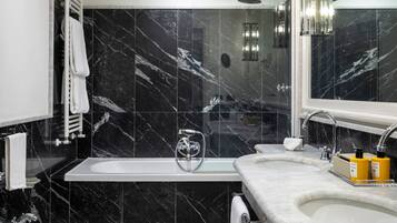 A modern bathroom with a bathtub, two sinks, a toilet, and a shower.