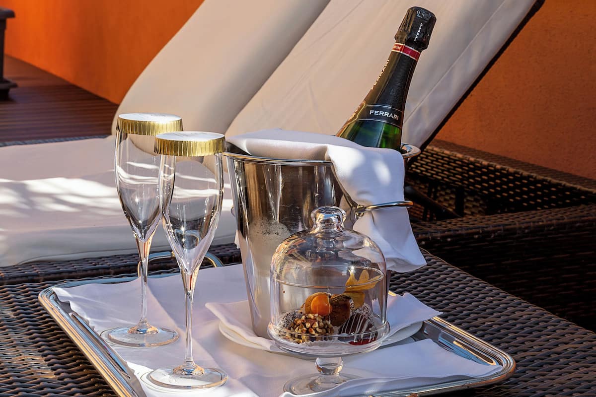 A tray with two champagne glasses, a bottle, and a small container on a wicker table.