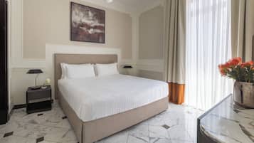 A hotel room with a large bed, a nightstand, a lamp, a painting on the wall, and a window with curtains.