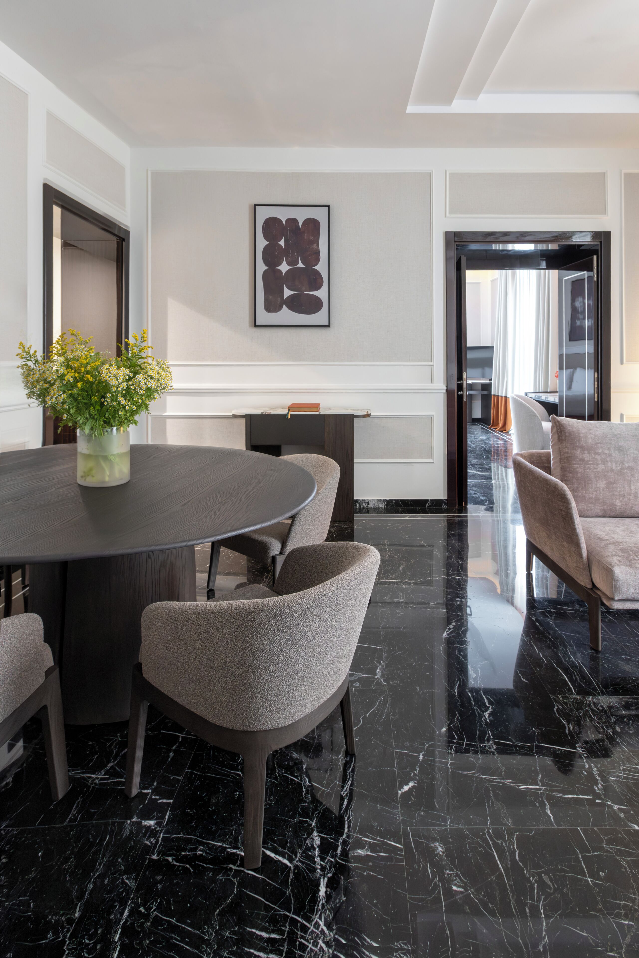 Habitació d'hotel moderna amb sòl de marbre, una taula de dinar rodona i seients còmodes.