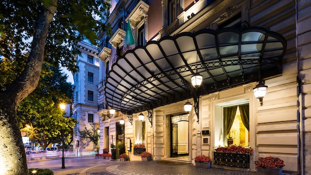 A hotel entrance with a covered entrance, a cobblestone pathway, and potted plants. - Baglioni Hotel Regina - The Leading Hotels of the World (Rome)