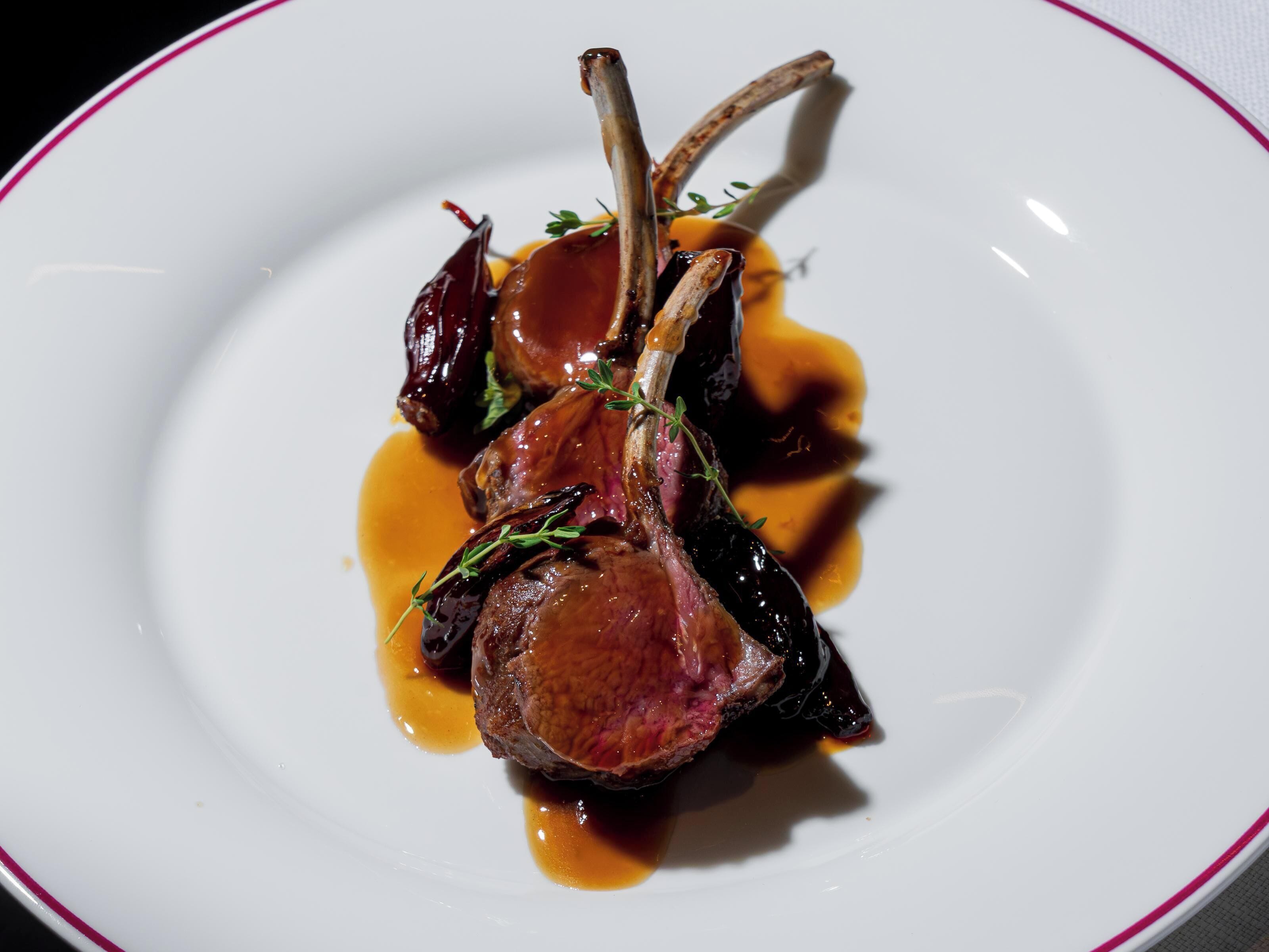 A plate with a dish of meat, possibly lamb, with a sauce and garnish.