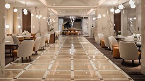 A spacious hotel lobby with a checkered floor, seating areas, a grand piano, and a staircase leading to an upper level. - Hôtel Barrière Le Gray d'Albion (Cannes)