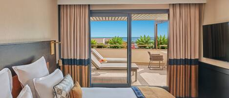 A hotel room with a large bed, a TV, and a balcony with a view of the ocean.