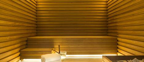 Una sauna con listones de madera, un banco, una copa y una toalla.