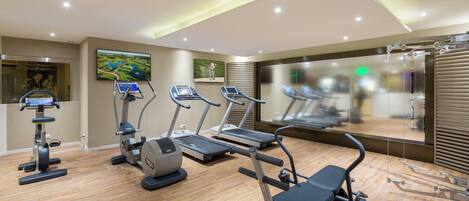 A modern gym with treadmills, elliptical machines, and a weight bench.