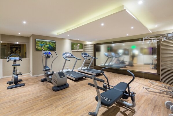 A modern gym with treadmills, elliptical machines, and a weight bench.