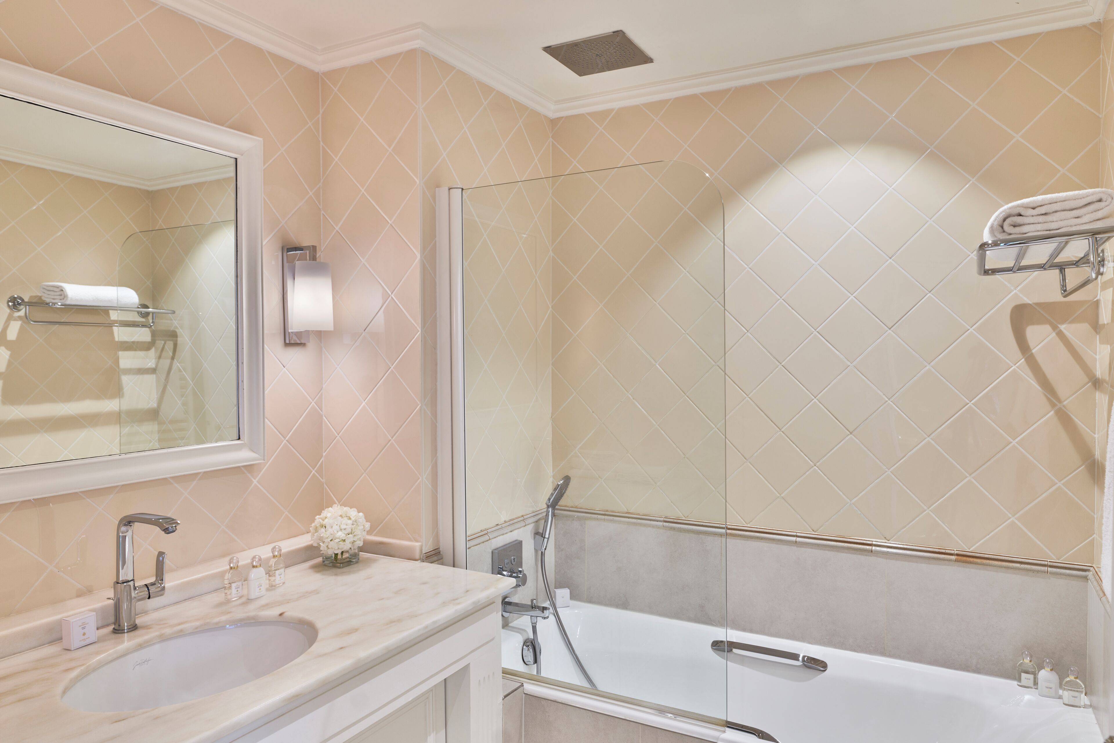 A bathroom with a sink, mirror, and a glass-enclosed shower.