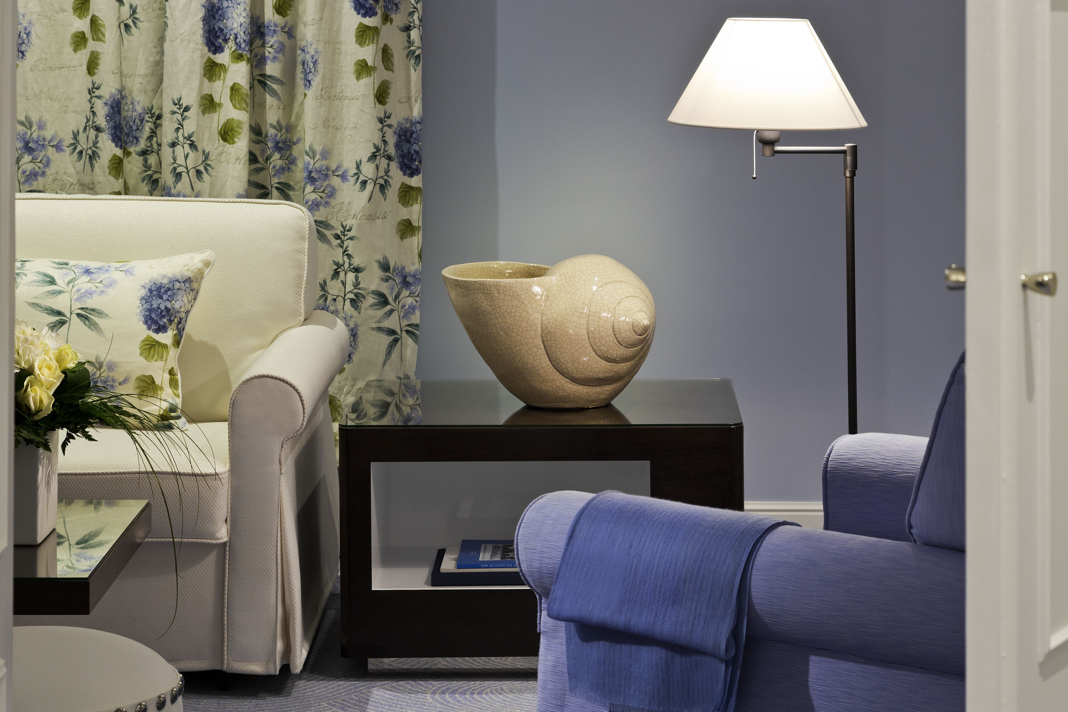Een moderne woonkamer met een bank, bijzettafeltje, lamp en decoratieve schaal.