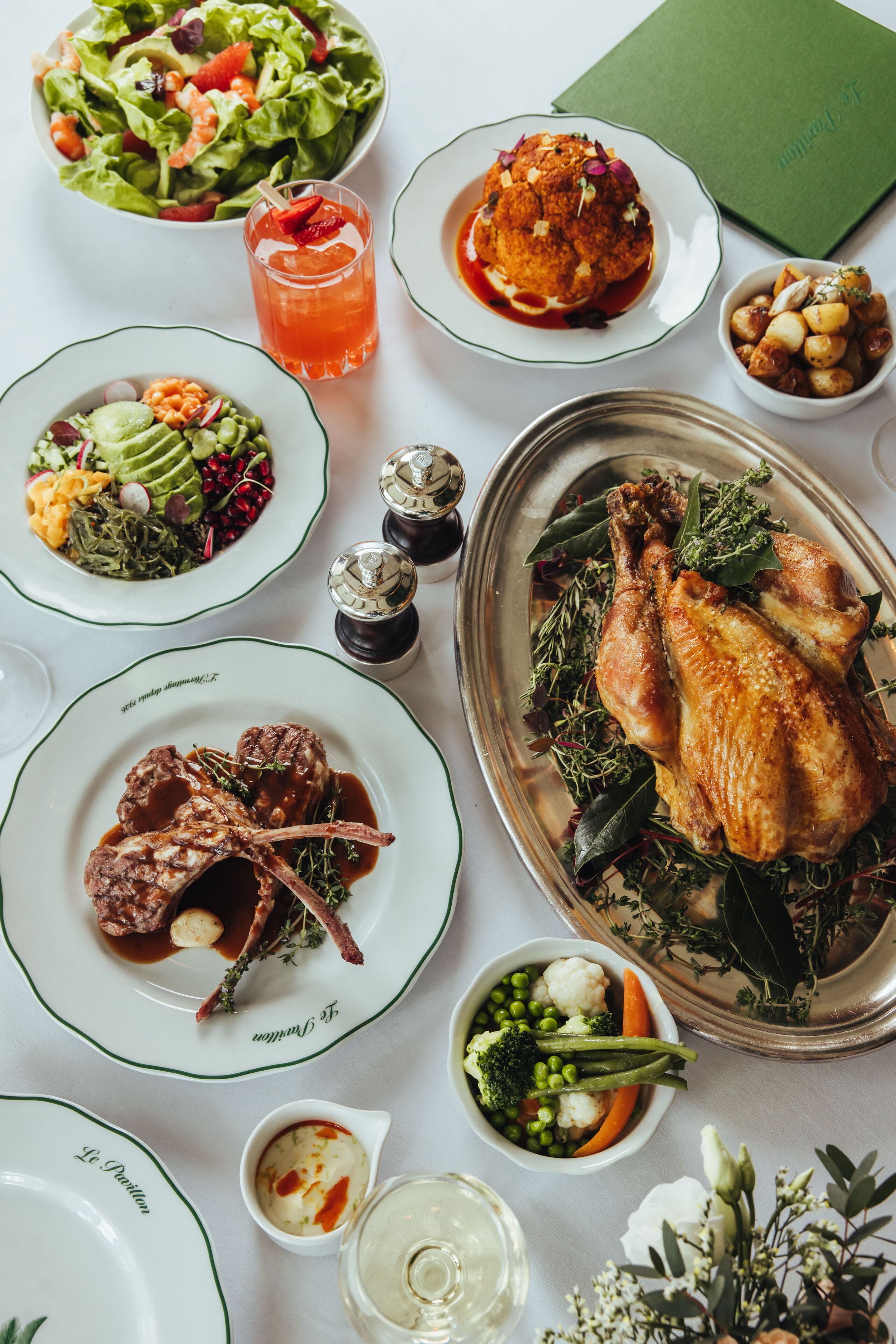 A table set with various dishes including a roasted chicken, salad, and multiple side dishes.