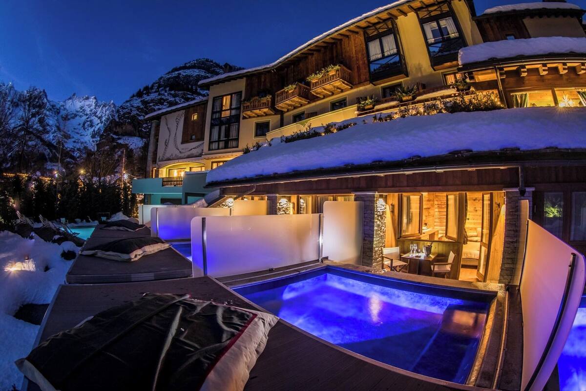 A luxurious resort with a heated outdoor pool, snow-covered surroundings, and a well-lit dining area.
