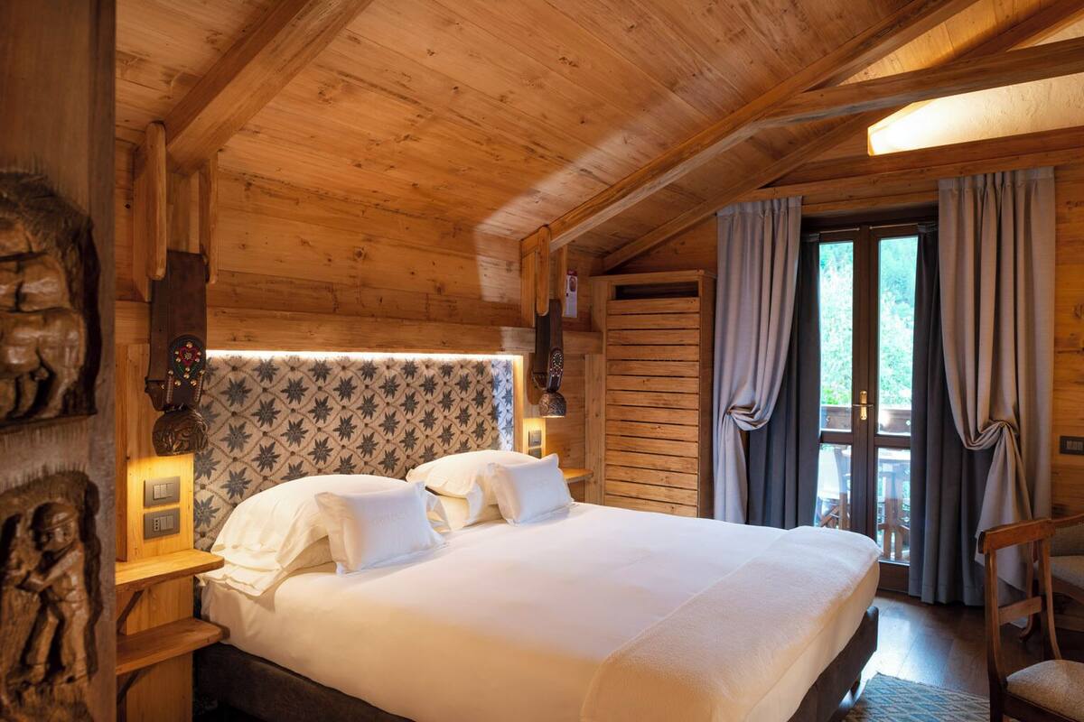 A wooden cabin-style room with a bed, a desk, and a chair.