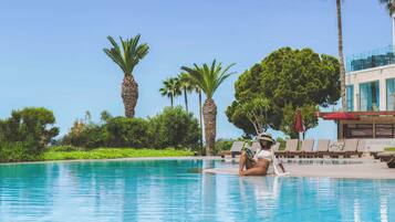 Un área de piscina con sillas de descanso y palmeras.