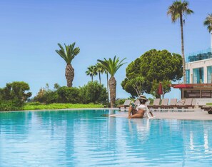 A pool area with lounge chairs and palm trees.
