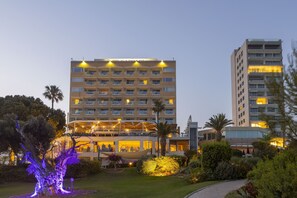 A hotel with multiple floors, outdoor seating, and well-lit gardens.
