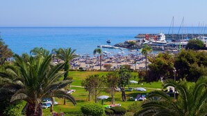 Una marina costiera con barche, una spiaggia con ombrelloni e una vista limpida del mare.
