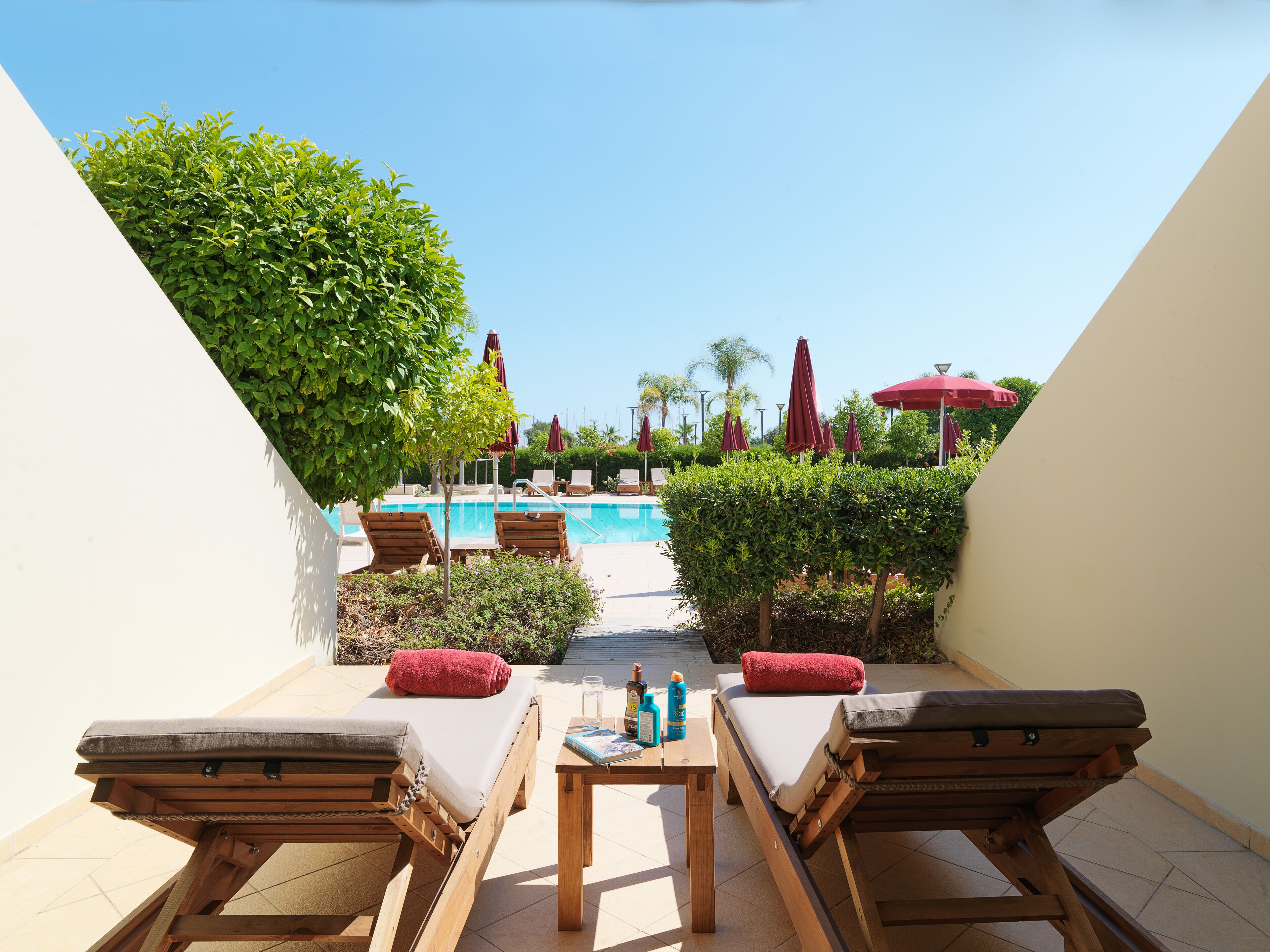 Uma área à beira da piscina com espreguiçadeiras, uma mesa com comodidades e vista desobstruída para a piscina.