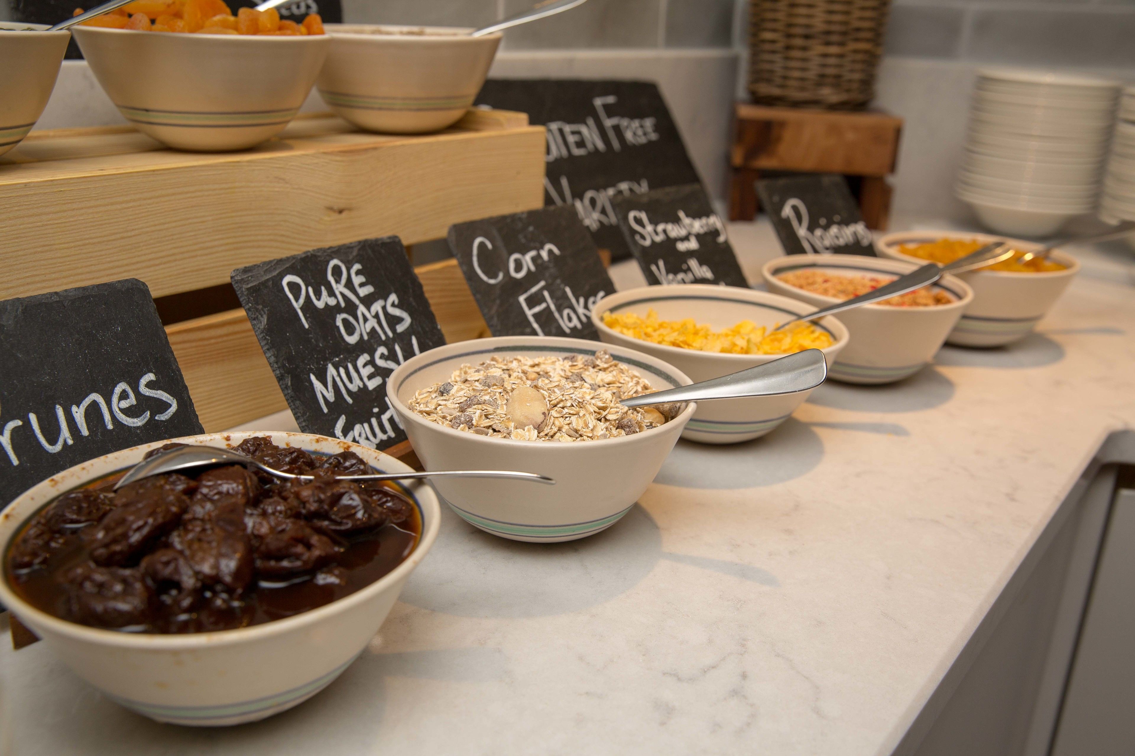 A breakfast buffet with various food options including oatmeal, granola, and fruit.