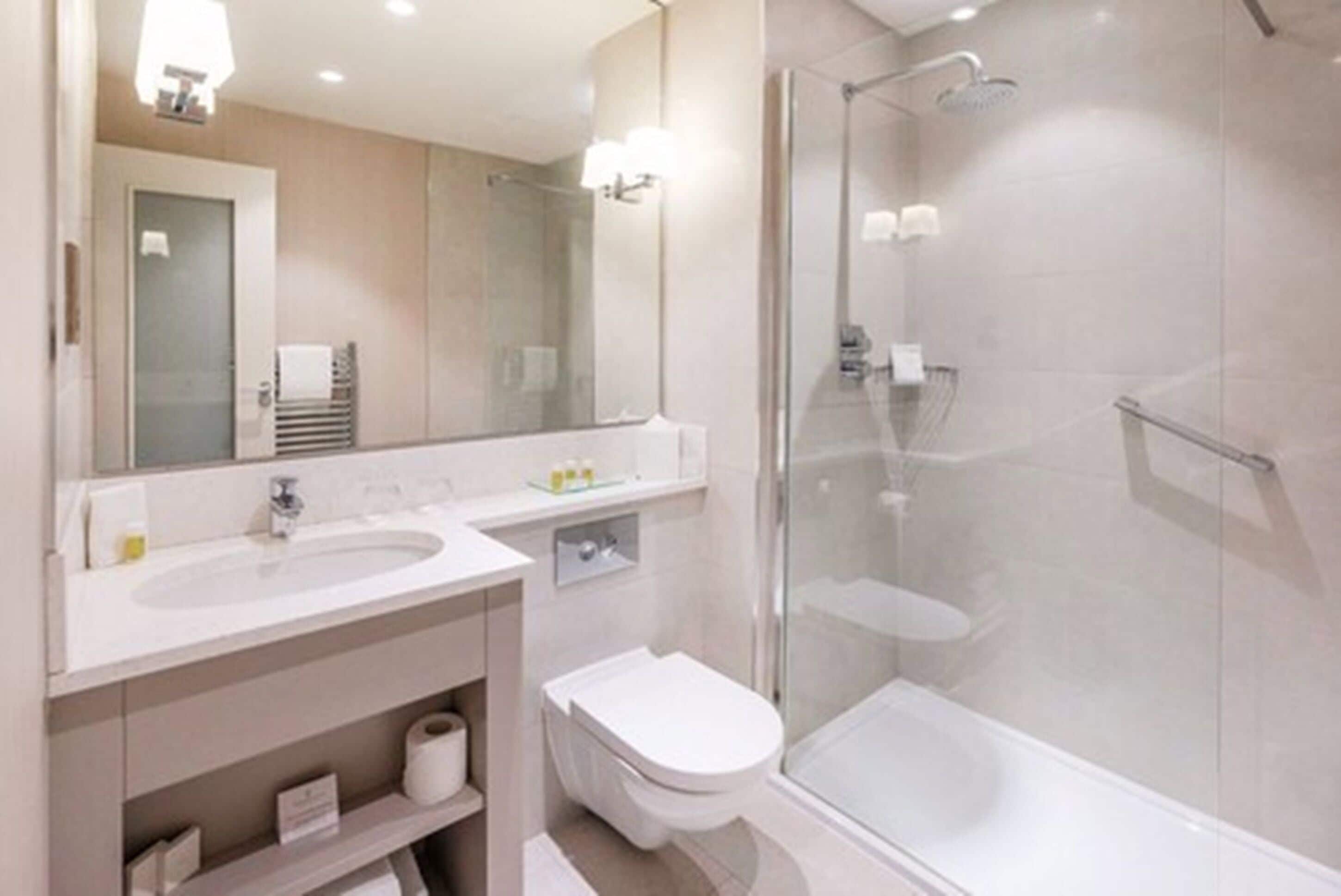 A modern bathroom with two sinks, a toilet, and a glass-enclosed shower.