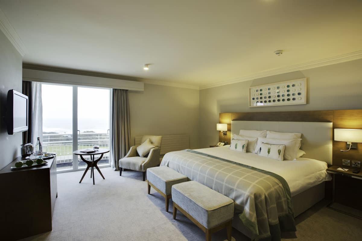 A hotel room with a large bed, a desk, a chair, and a view of the outdoors.