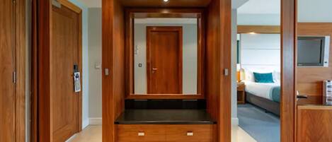 A room with a wooden wardrobe, a bed, and a television.