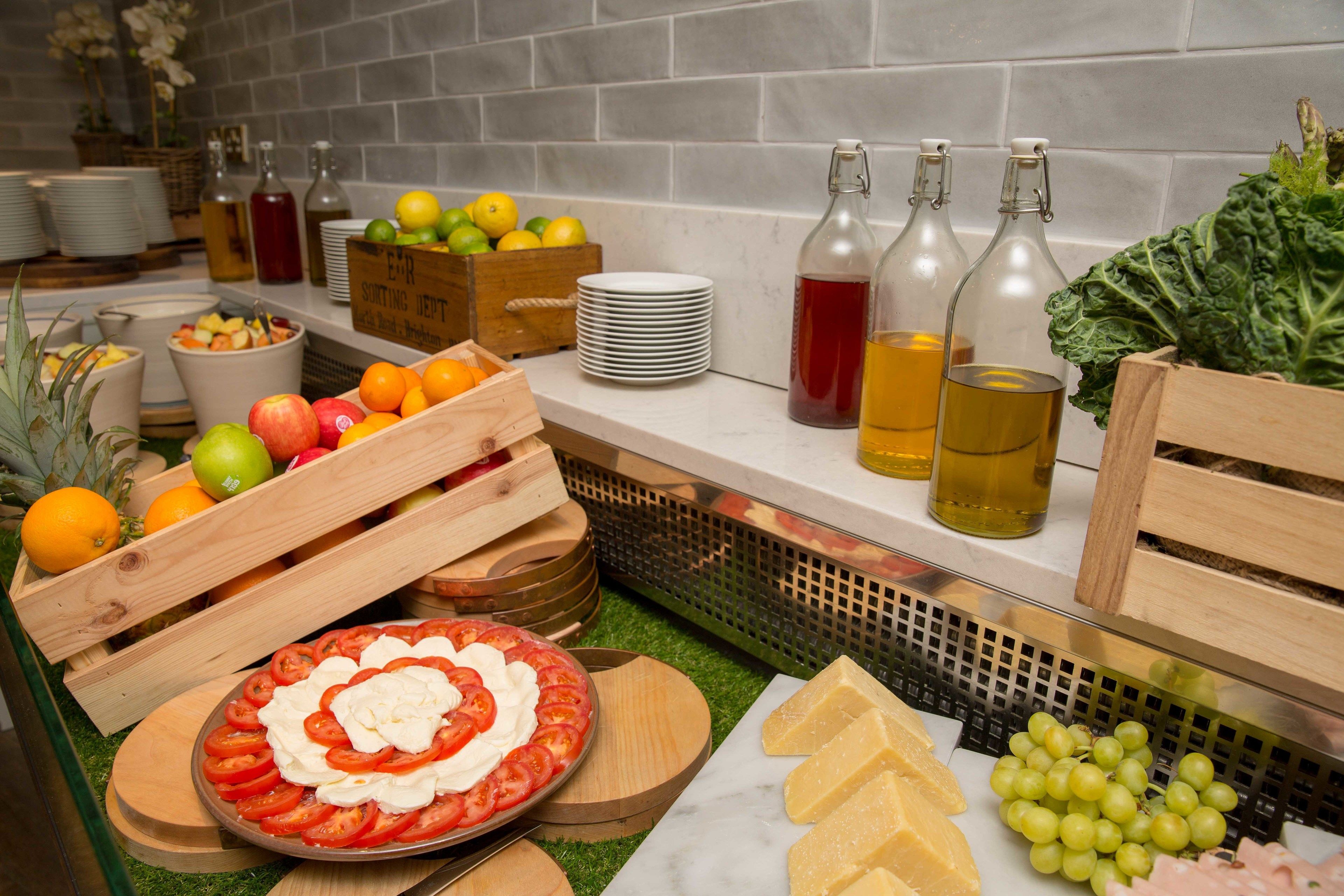A buffet setup with various fruits, cheeses, and a decorated tomato platter.