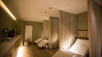 Un cuarto de spa con una camilla de masaje, un pequeño mostrador de recepción y una silla de masaje fijada a la pared.
