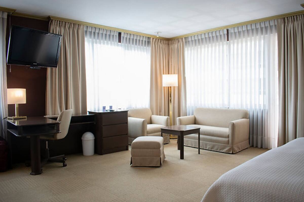 Una habitación de hotel con cama, escritorio, silla, sofá y televisión.