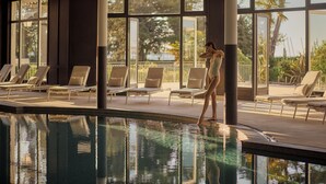 Zona de piscina con sillones de descanso y una persona junto a la piscina.