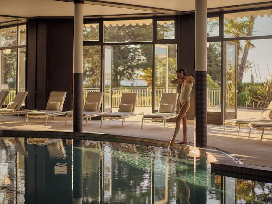 Ein Poolbereich mit Liegestühlen und einer Person am Pool.