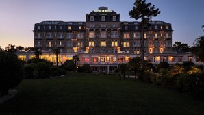 Un hotel grande de varios pisos con estilo arquitectónico europeo clásico, que cuenta con numerosos balcones y una fachada bien iluminada.